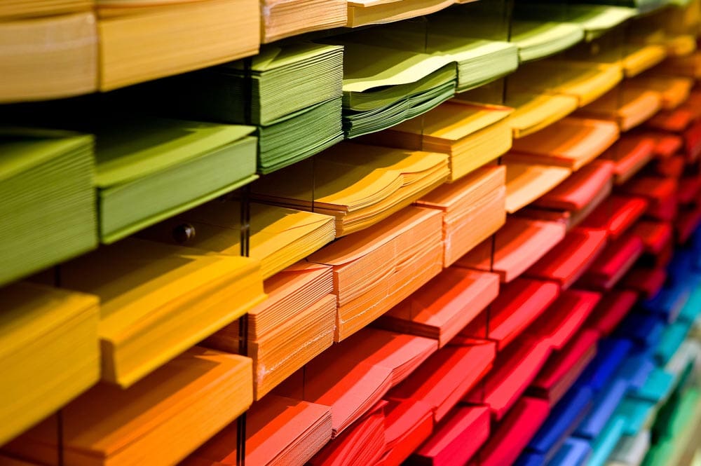 Stacks of colorful paper arranged by color, including yellow, green, orange, red, blue and teal.