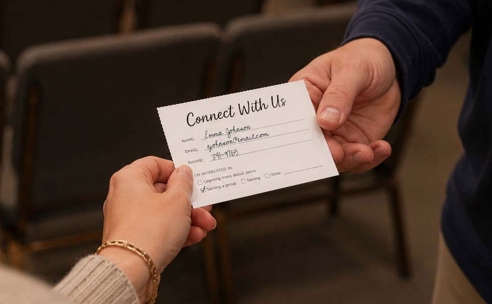 Person handing a team member a completed church connection card torn along a perforated edge.