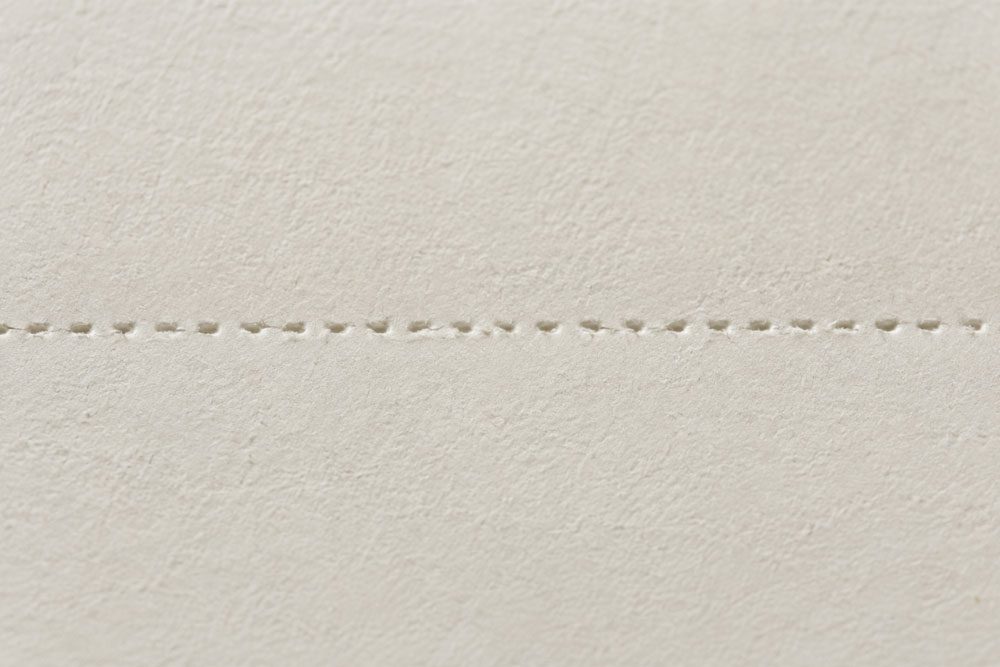 Close-up of micro perforation cuts across an off-white sheet of paper.