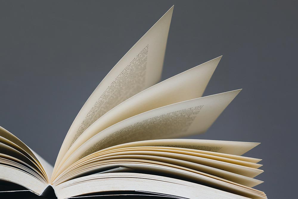 Close-up of an open book with pages bending and turning along the spine.