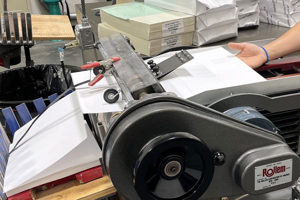 Commercial perforation machine creating perforated lines in sheets of white paper.