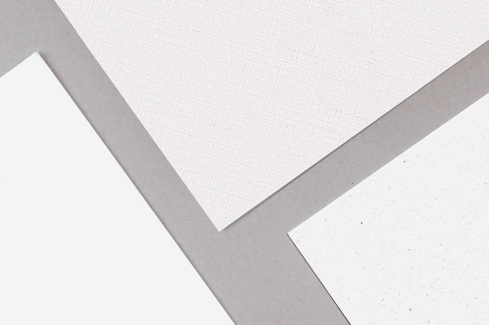 Close-up comparison of white uncoated papers with smooth, textured and fiber-flecked surfaces.